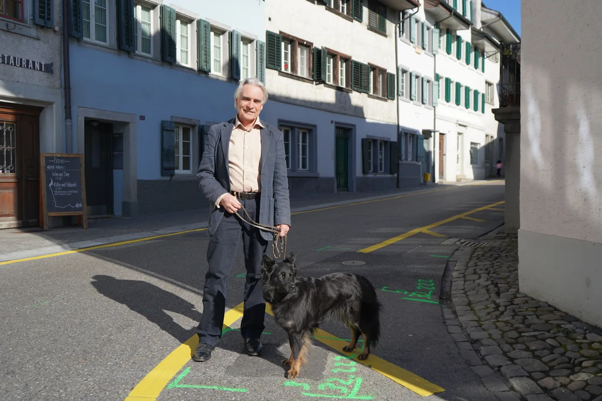 Ein Mann mit Hund steht auf einer Strasse.